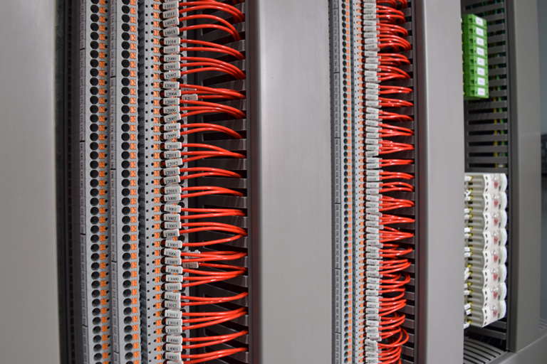 Bornes de conexão PSMR em trilho DIN com condutores vermelhos identificados por marcadores numerados em painel elétrico industrial